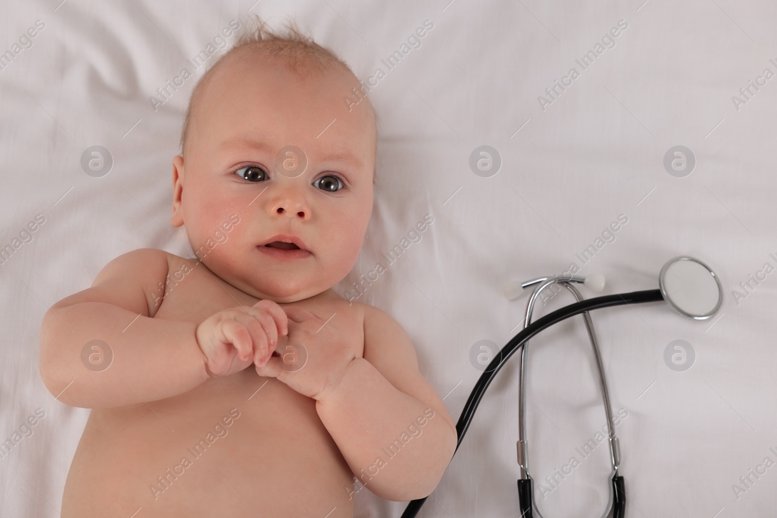 Photo of Cute little baby with stethoscope in clinic, top view