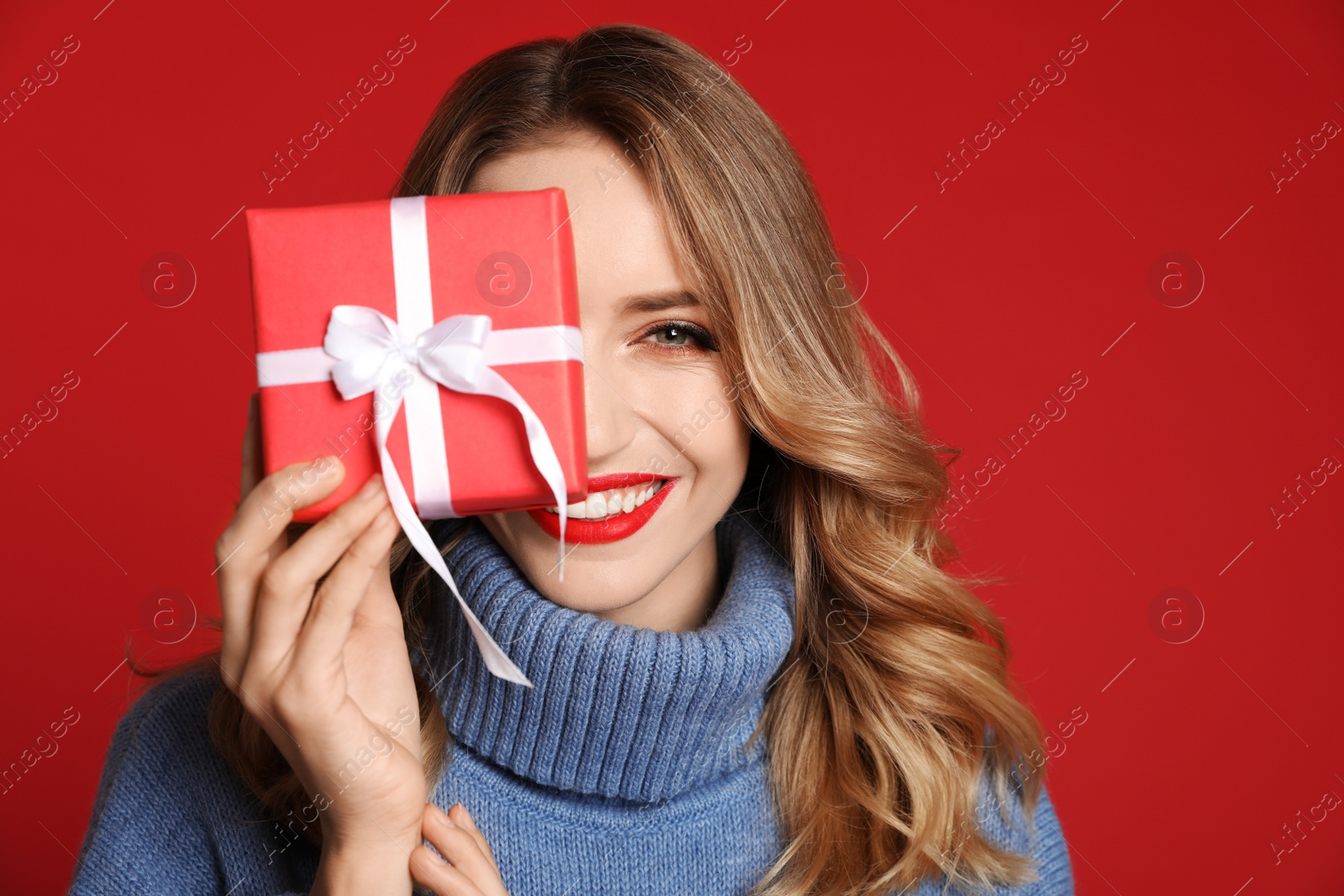 Photo of Happy young woman with Christmas gift on red background