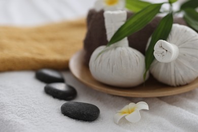 Spa stones, flowers and herbal bags on towel indoors, closeup