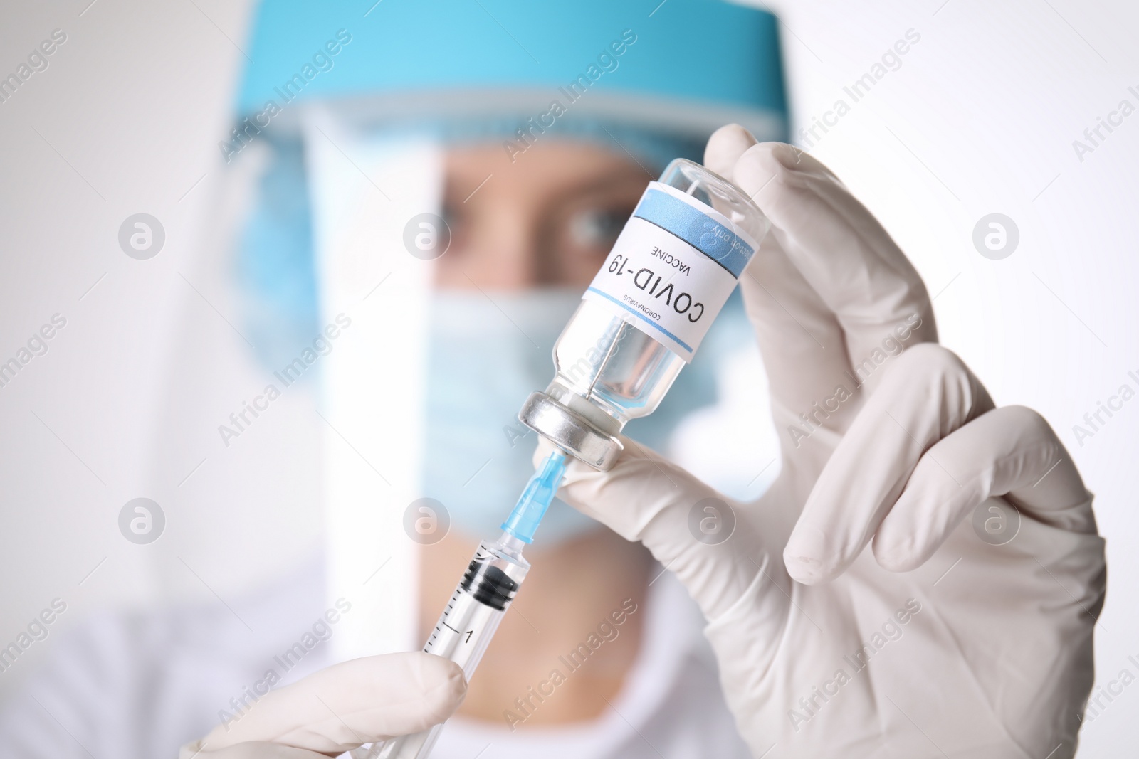 Photo of Doctor filling syringe with vaccine against Covid-19 on white background, closeup