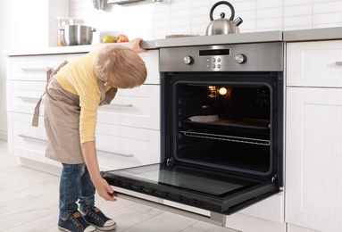 Little boy baking cookies in oven at home