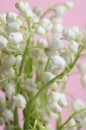 Photo of Beautiful lily of the valley flowers on pink background, closeup