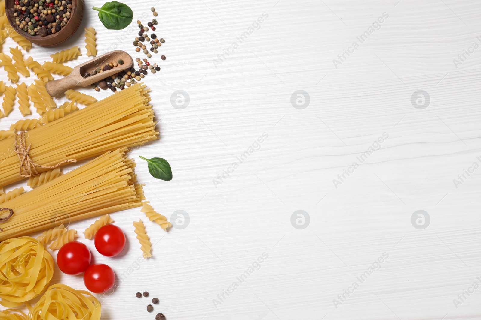 Photo of Flat lay composition with different types of pasta on white wooden table, space or text