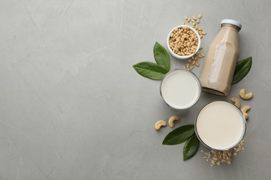 Different vegan milks and ingredients on light grey table, flat lay. Space for text