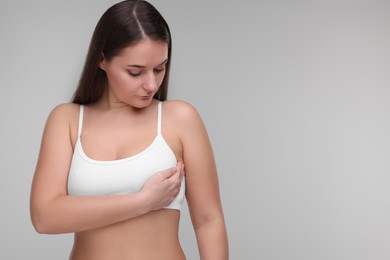 Mammology. Woman doing breast self-examination on light grey background, space for text