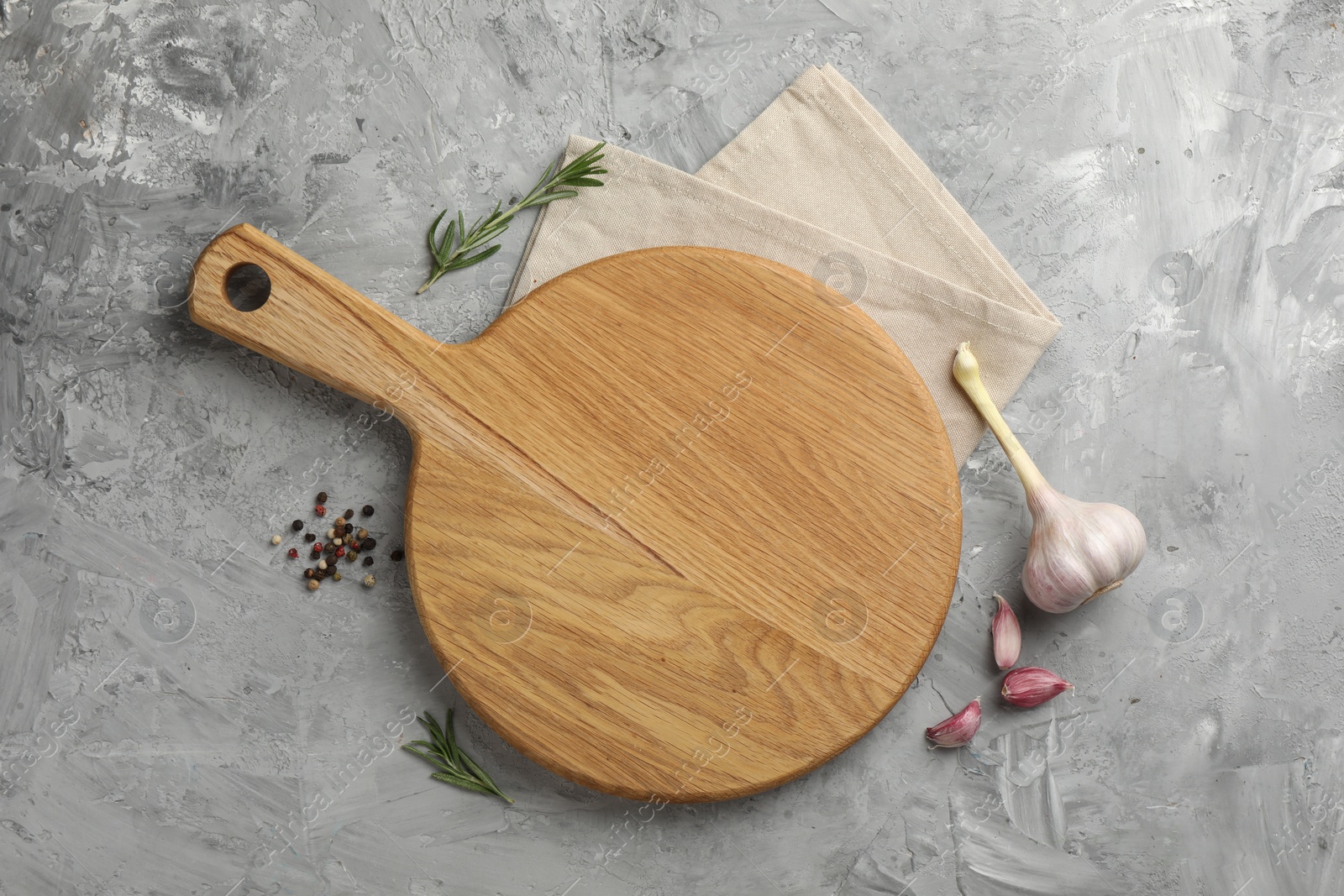 Photo of Cutting board, garlic, spices and rosemary on grey textured table, flat lay. Space for text