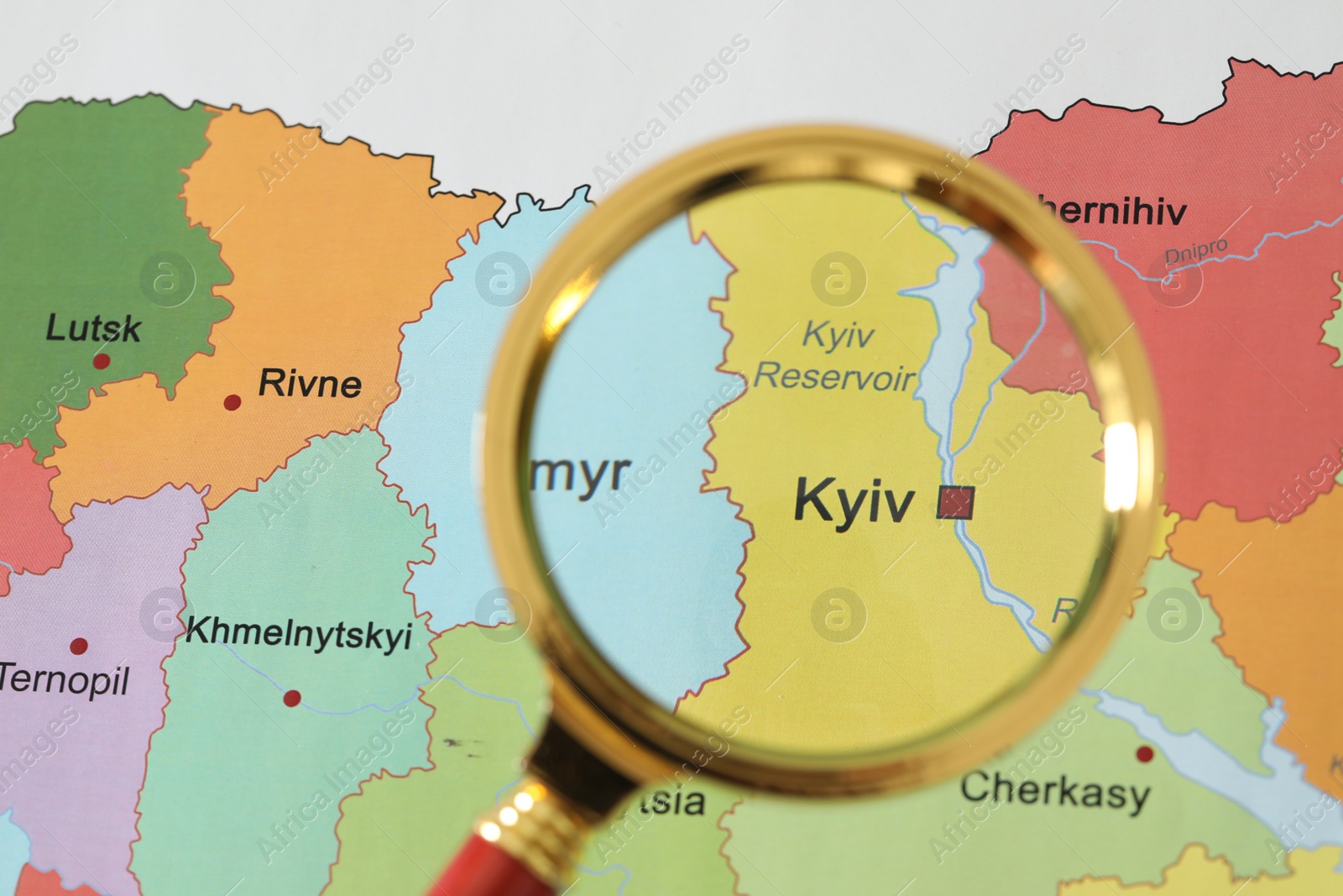 Photo of Golden magnifying glass above Kyiv region on map of Ukraine, closeup