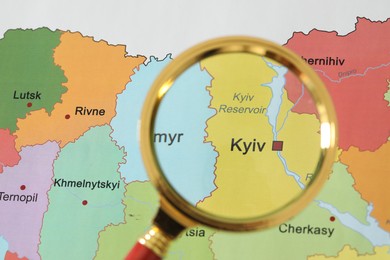 Golden magnifying glass above Kyiv region on map of Ukraine, closeup