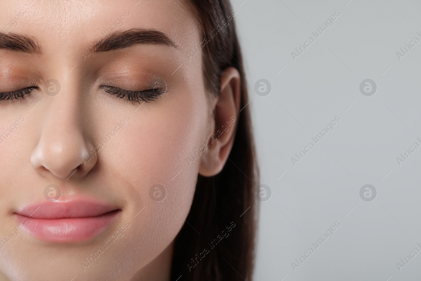 Photo of Beautiful young woman with healthy skin on light grey background, closeup. Space for text