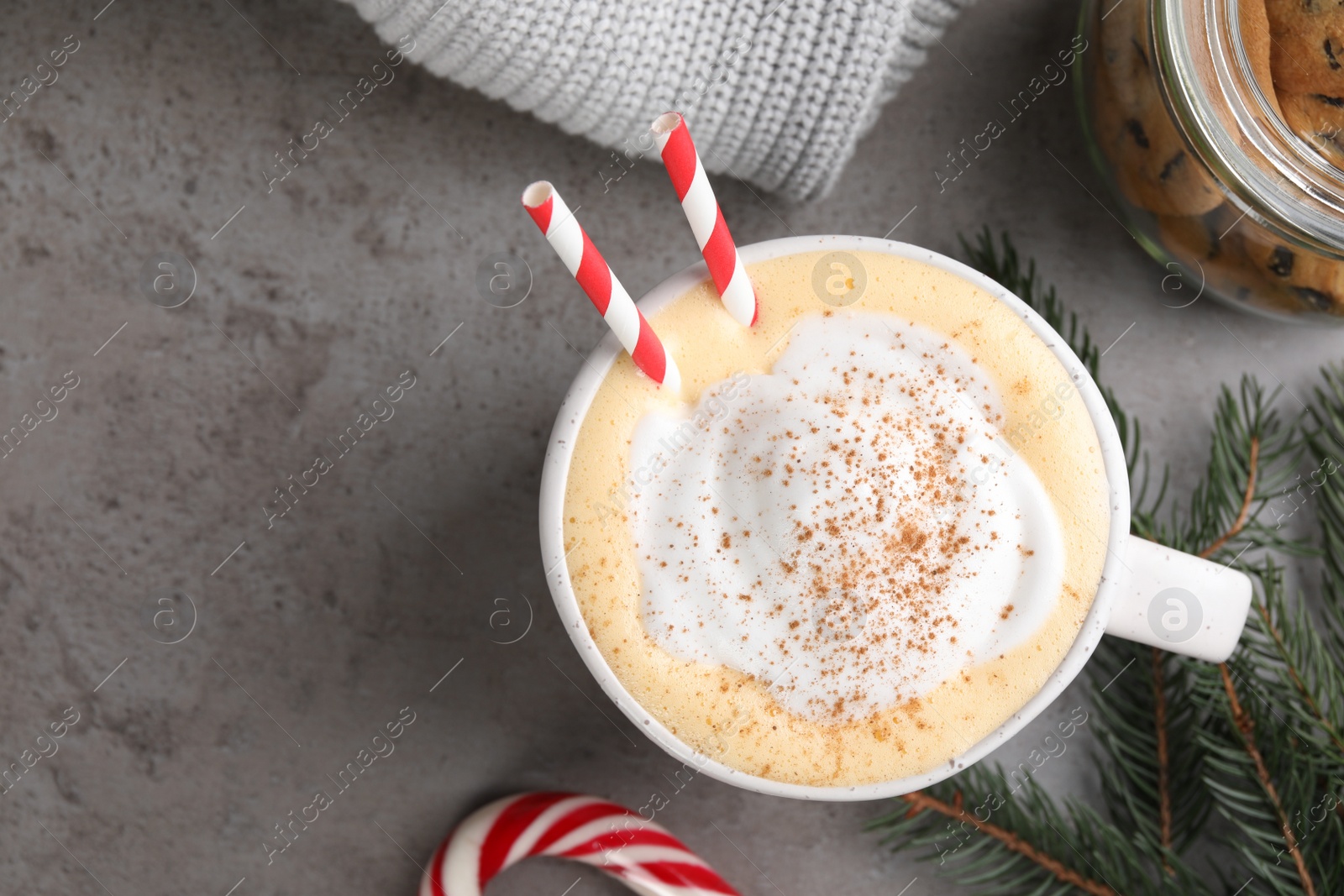 Photo of Cup of delicious eggnog with cinnamon on gray table, flat lay. Space for text