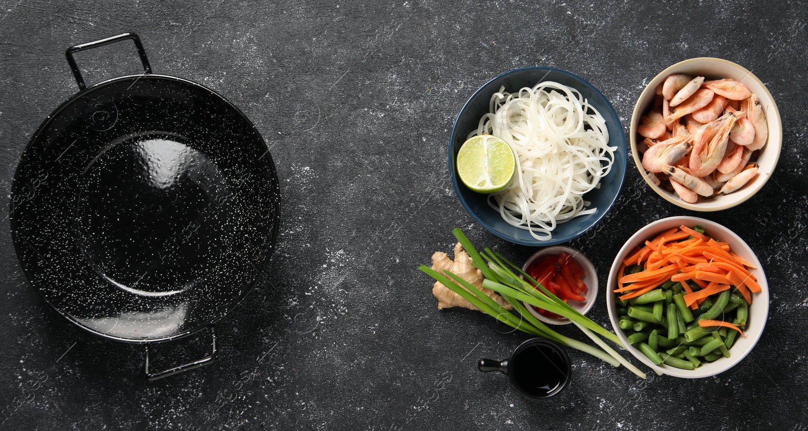 Photo of Flat lay composition with black wok and products on dark textured table