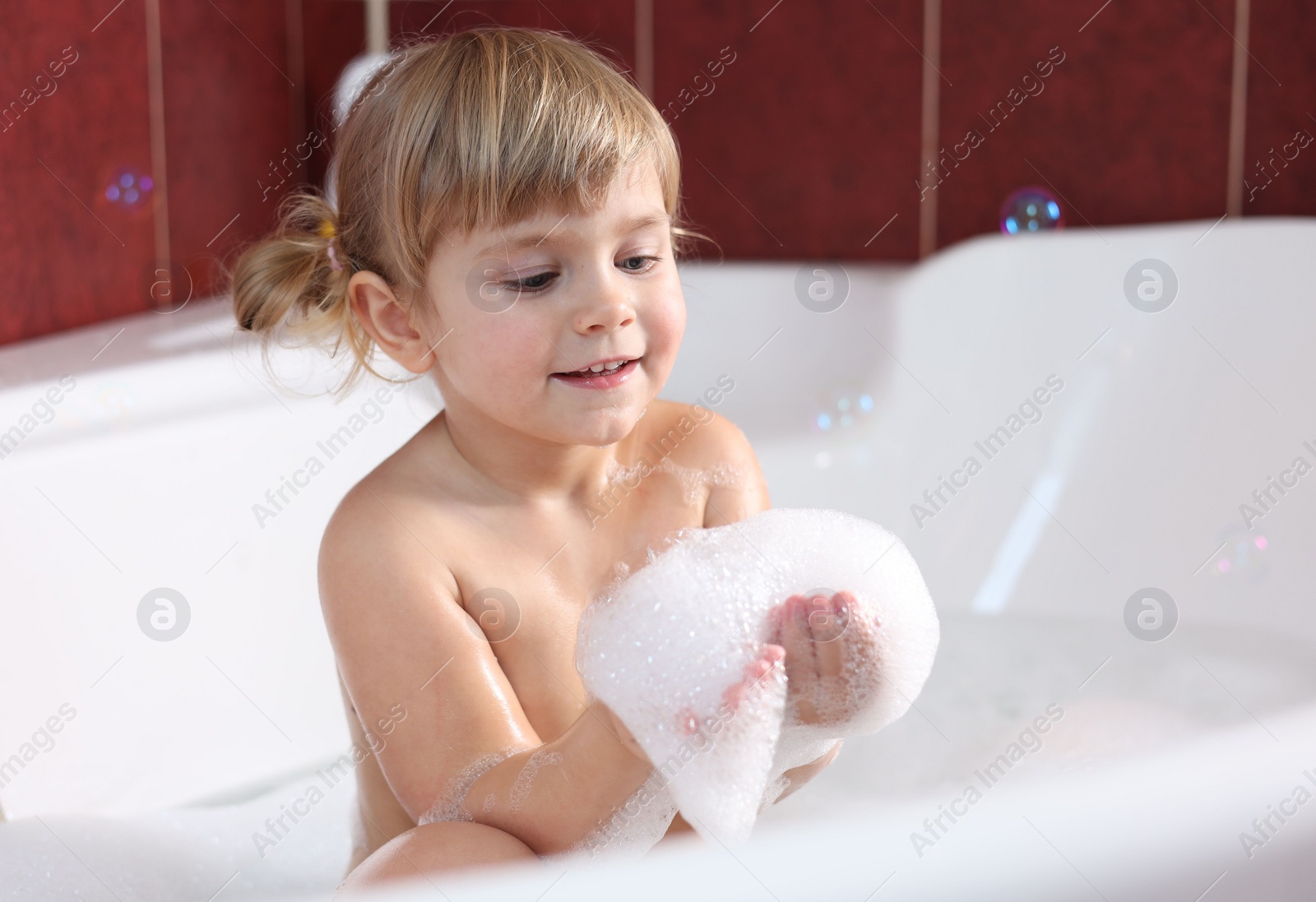 Photo of Little girl bathing in tub at home