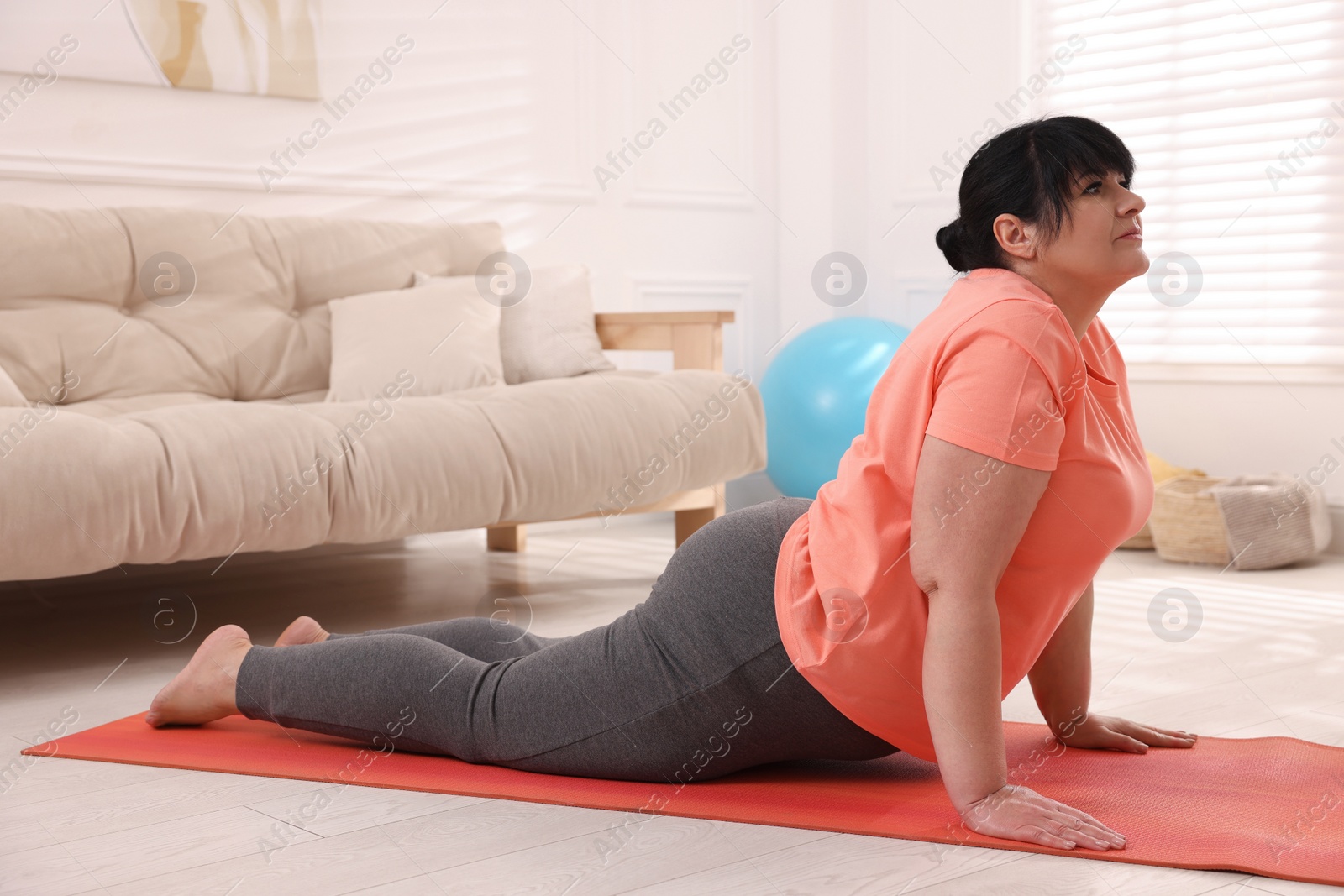 Photo of Overweight mature woman doing exercise on yoga mat at home