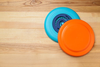 Plastic frisbee disks on wooden background, flat lay. Space for text