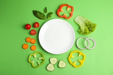 Photo of Flat lay composition with fresh salad ingredients on green background, space for text