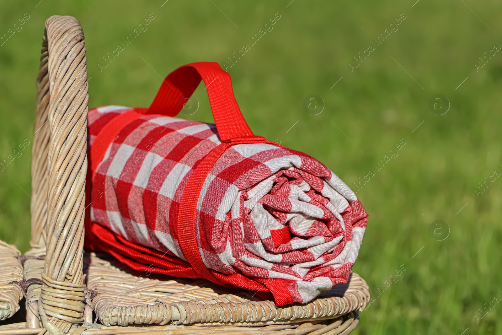 Photo of Checkered tablecloth on picnic basket outdoors, closeup