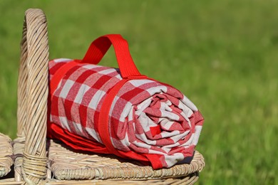 Photo of Checkered tablecloth on picnic basket outdoors, closeup