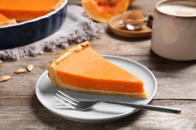 Plate with piece of fresh delicious homemade pumpkin pie on wooden table