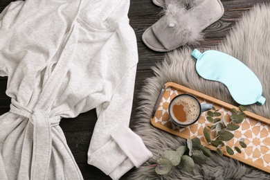 Photo of Flat lay composition with fluffy slippers and bath robe on black wooden background. Comfortable home outfit