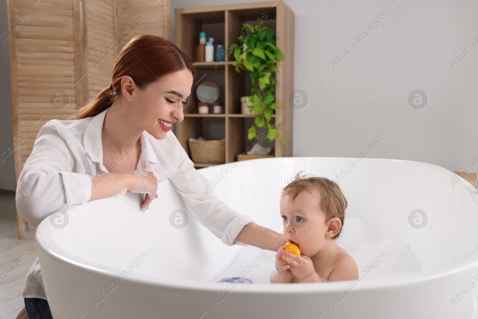 Photo of Mother washing her little baby in tub at home