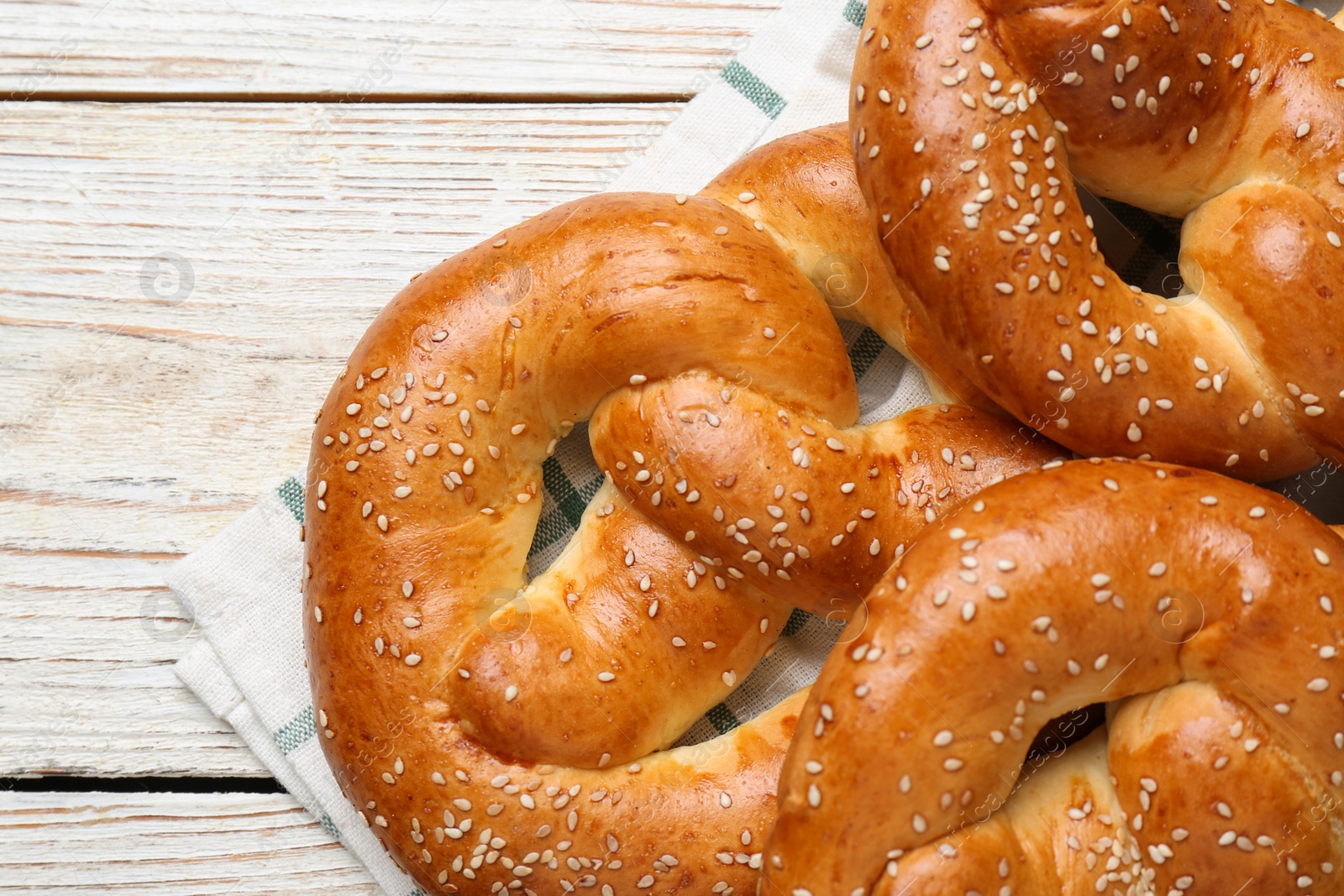 Photo of Delicious pretzels with sesame seeds on white wooden table, closeup