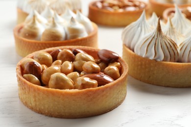 Photo of Many different tartlets on white wooden table, closeup. Delicious dessert