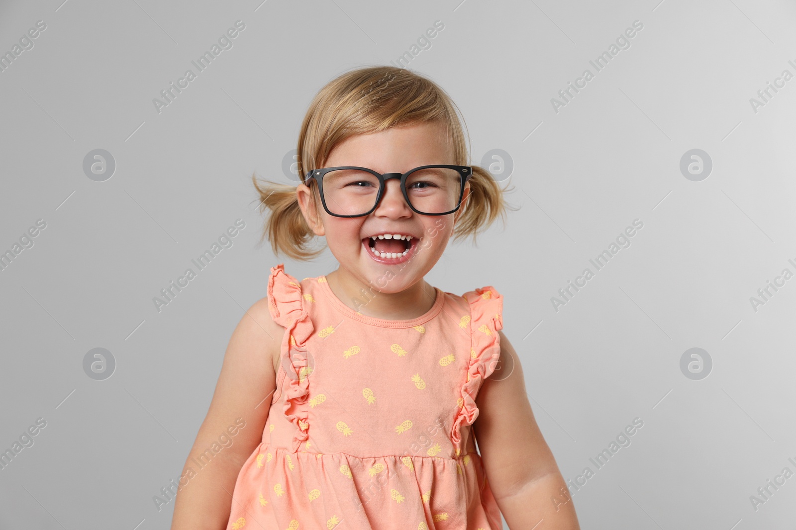 Photo of Cute little girl in glasses on light grey background