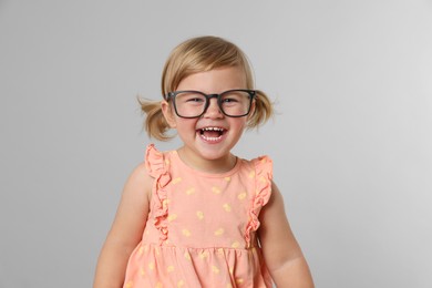 Cute little girl in glasses on light grey background