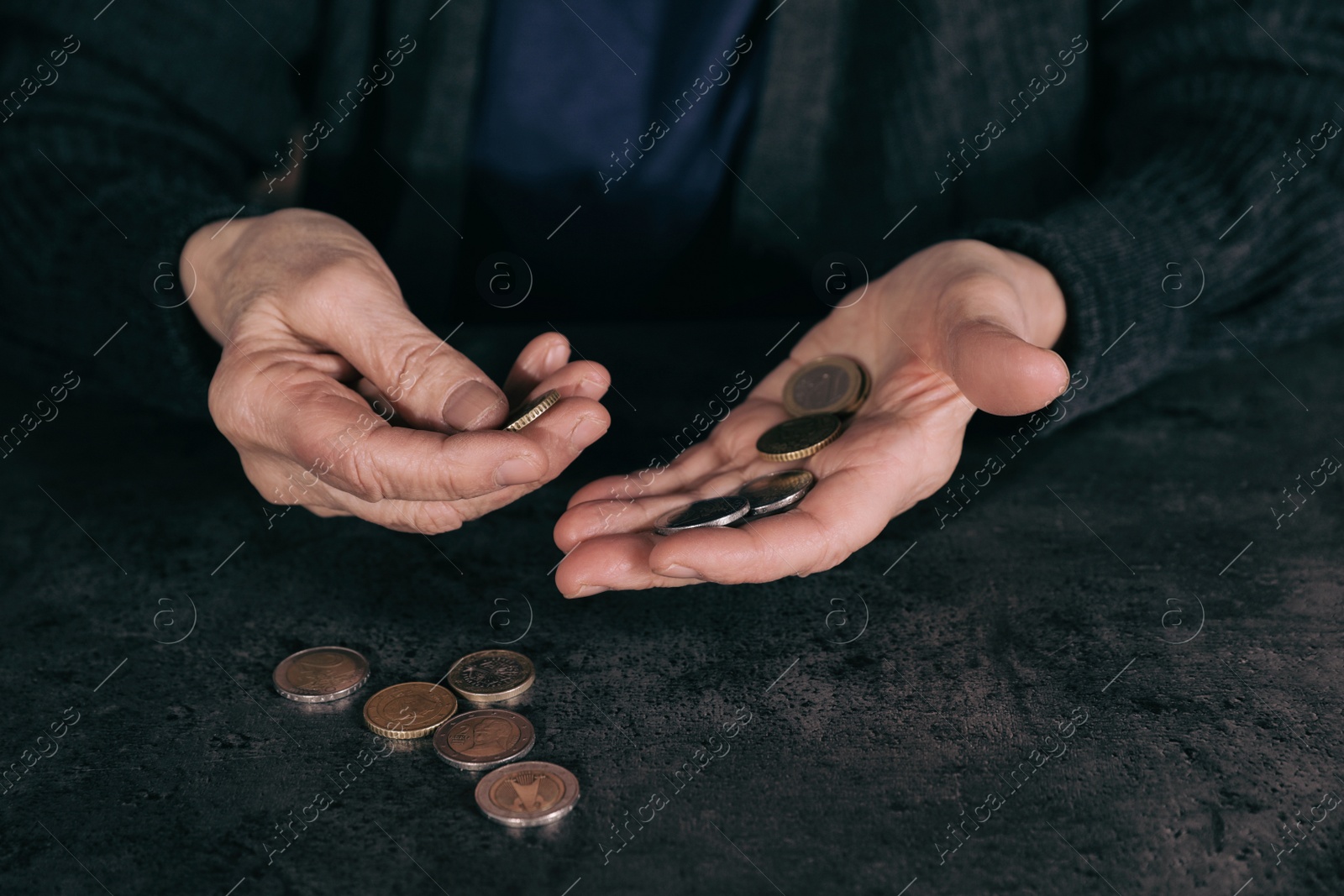 Photo of Poor mature woman counting coins at table, closeup