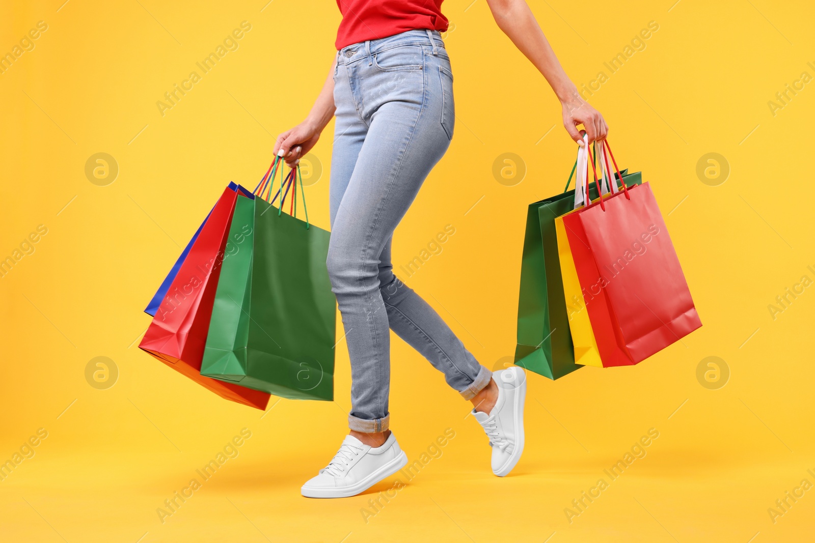 Photo of Woman with shopping bags on yellow background, closeup