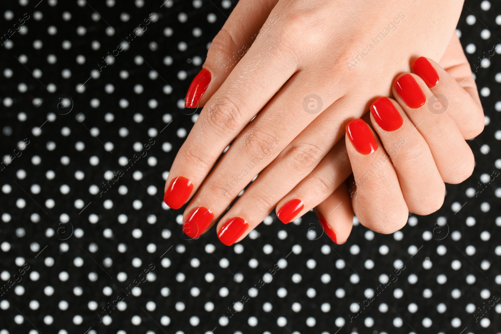 Photo of Woman showing manicured hands with red nail polish on patterned background, top view. Space for text