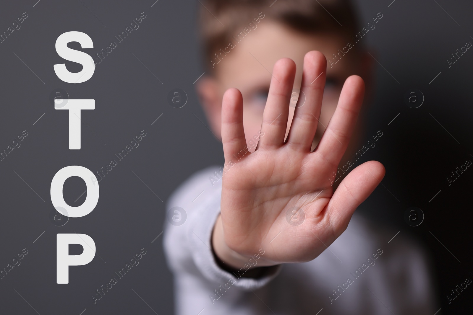 Image of No child abuse. Boy making stop gesture on grey background, selective focus