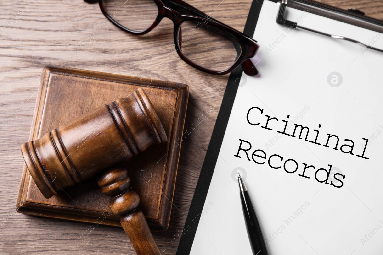 Image of Clipboard with words CRIMINAL RECORD and gavel on wooden table, flat lay