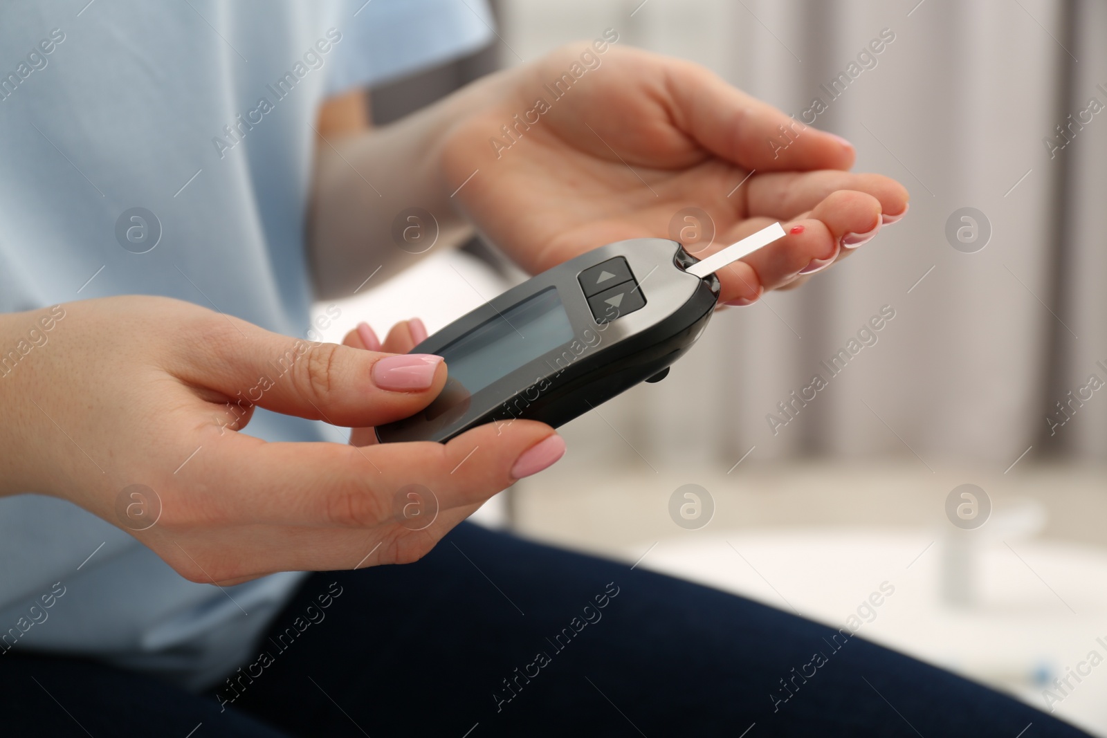 Photo of Diabetes. Woman checking blood sugar level with glucometer at home, closeup