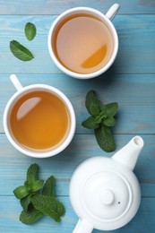 Hot aromatic mint tea on light blue wooden table, flat lay