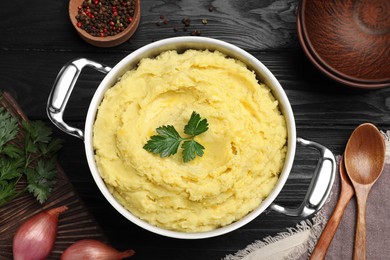 Photo of Pot of tasty mashed potatoes with parsley on black wooden table, flat lay