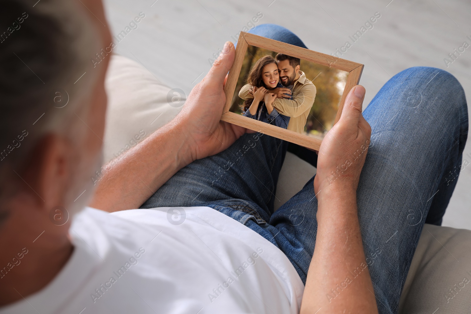 Image of Senior man holding frame with photo portrait of couple at home, closeup