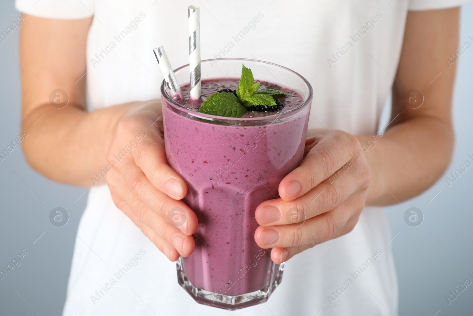 Photo of Young woman holding glass of tasty blackberry smoothie, closeup