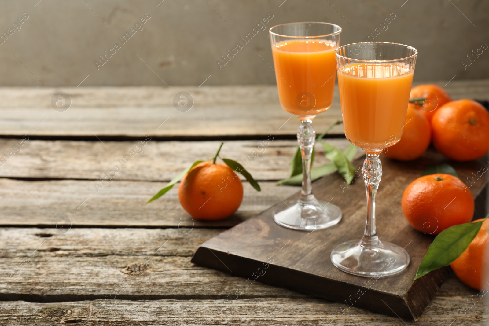 Photo of Delicious tangerine liqueur and fresh fruits on wooden table, space for text
