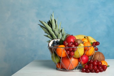 Photo of Assortment of fresh exotic fruits on white wooden table against light blue background. Space for text