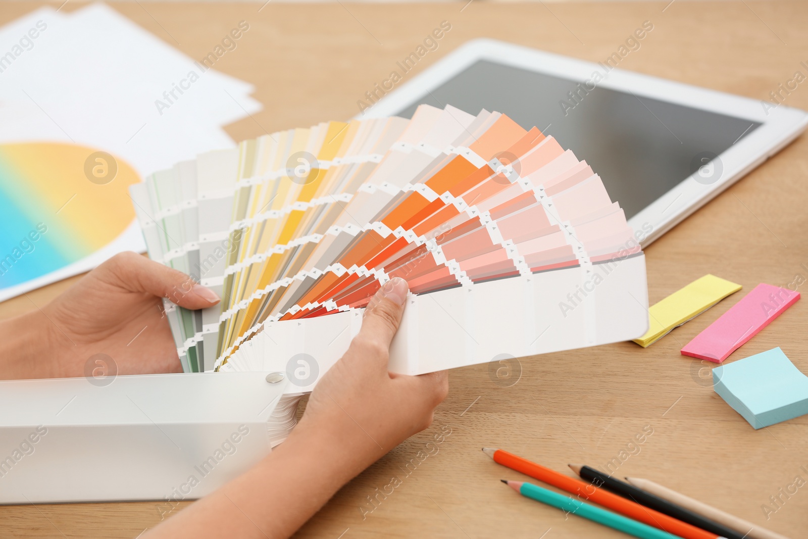 Photo of Designer with paint color palette samples at table, closeup