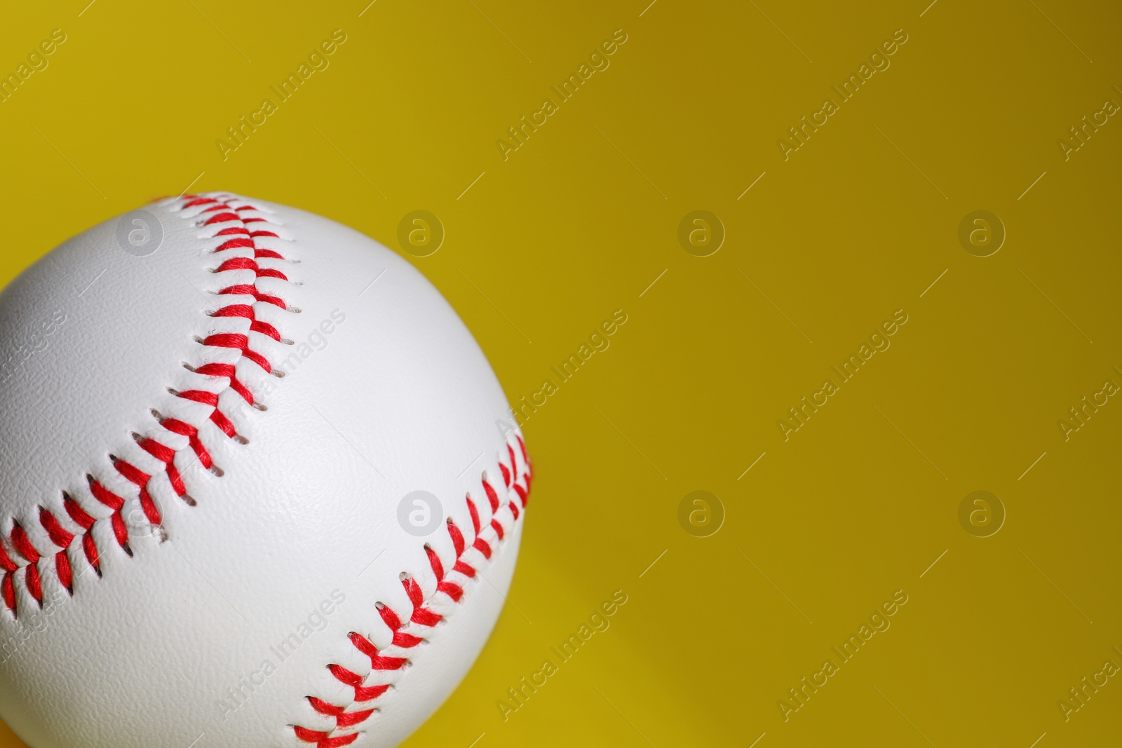 Photo of One baseball ball on yellow background, closeup. Space for text