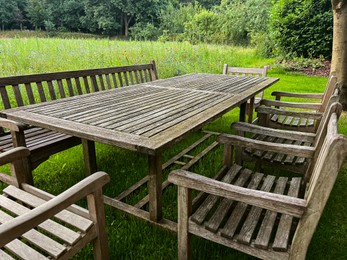 Wooden table with bench and chairs in garden. Landscape design