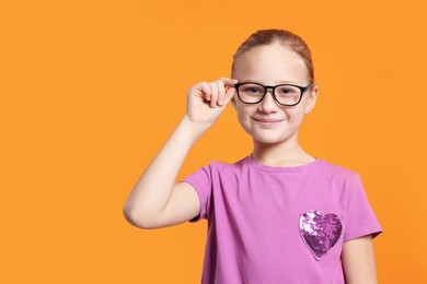 Portrait of cute girl in glasses on orange background