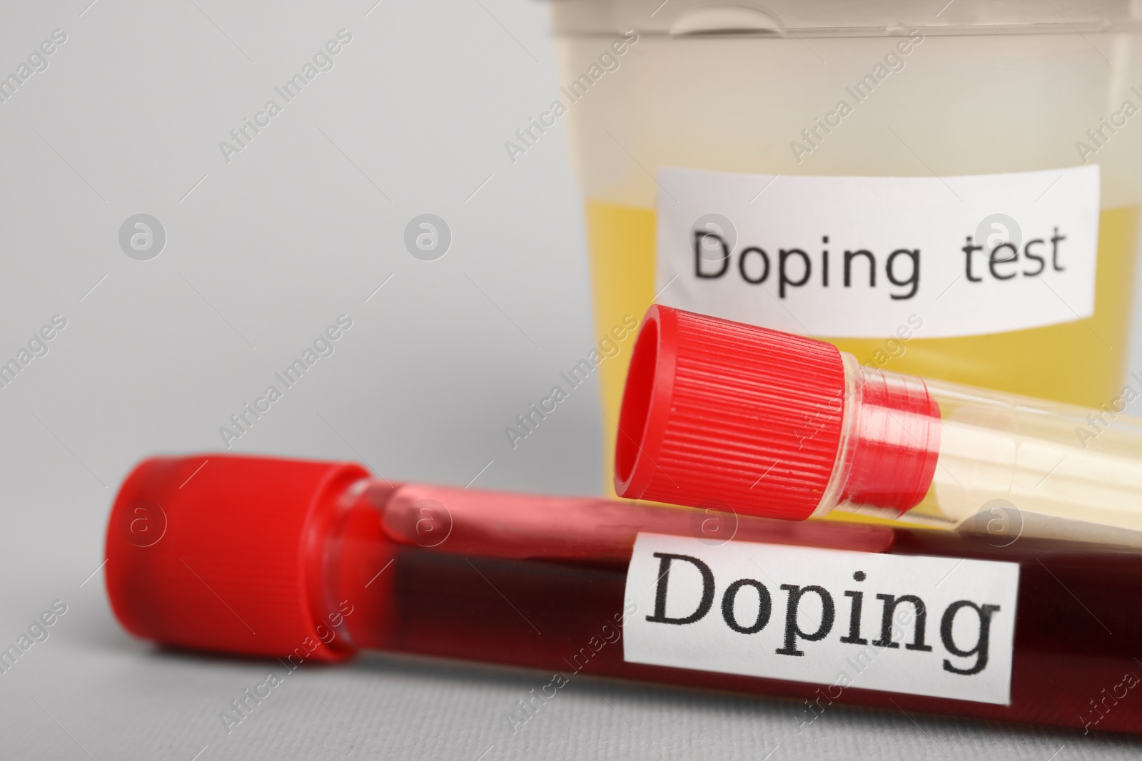 Photo of Closeup view of jar and test tubes with samples on light grey background. Doping control