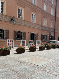 Photo of WARSAW, POLAND - JULY 17, 2022: Building with open windows and flower decor on sunny day