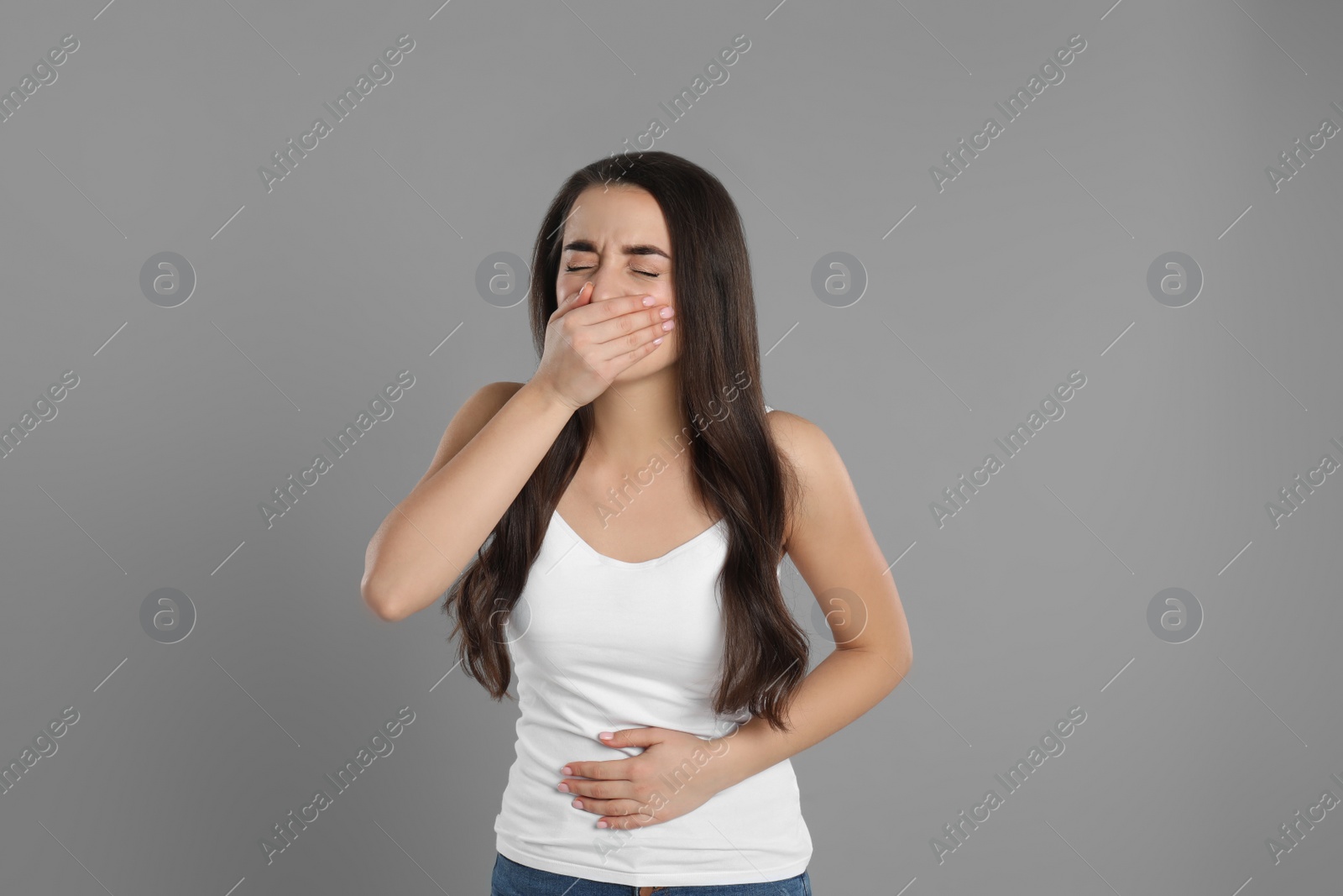 Photo of Young woman suffering from nausea on grey background. Food poisoning