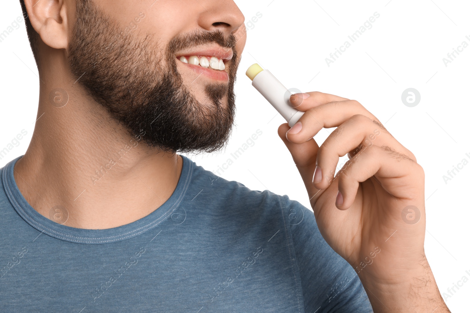 Photo of Young man applying lip balm on white background, closeup