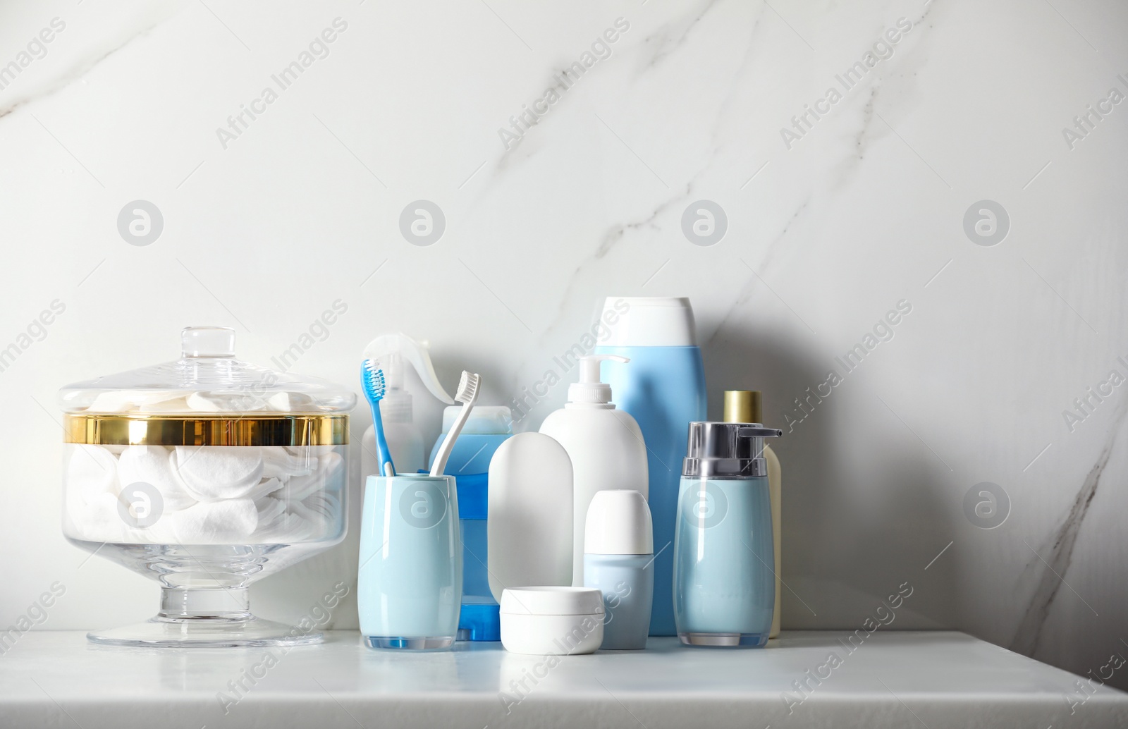 Photo of Roll-on deodorant and different toiletry on marble table near light wall