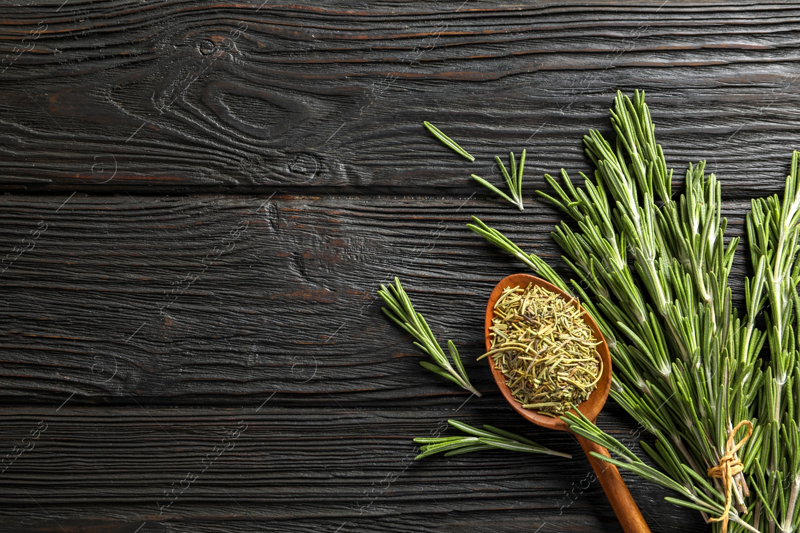 Photo of Spoon with dried rosemary and twigs on wooden table, top view